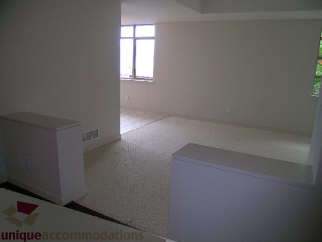 Spacious living room with large windows and neutral tones, perfect for relaxation. - 8601 Seascape Place, West Vancouver
