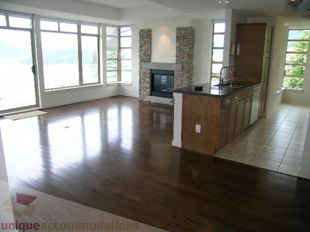 Open-concept living space with hardwood floors, a stone fireplace, and a kitchen island, perfect for a cozy retreat.