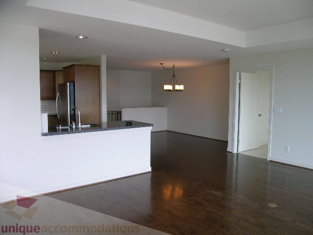Spacious open-concept living area with hardwood floors and a modern kitchen featuring granite countertops. - 8601 Seascape Place, West Vancouver