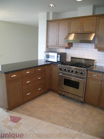 Bright kitchen with granite countertops, stainless steel appliances, and tiled backsplash. - 8601 Seascape Place, West Vancouver