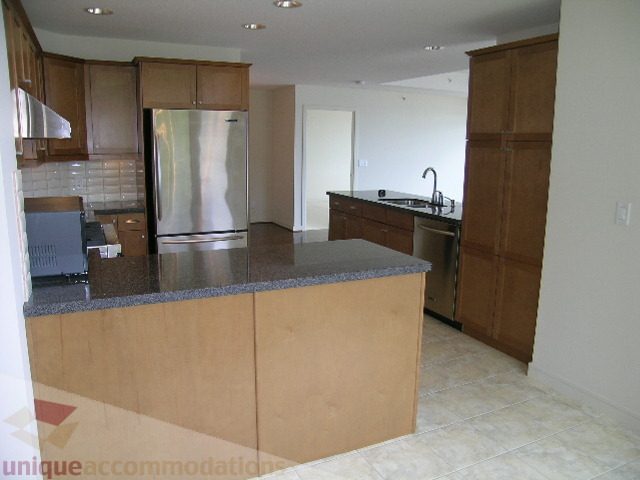 Modern kitchen with granite countertops and wooden cabinets. - 8601 Seascape Place, West Vancouver