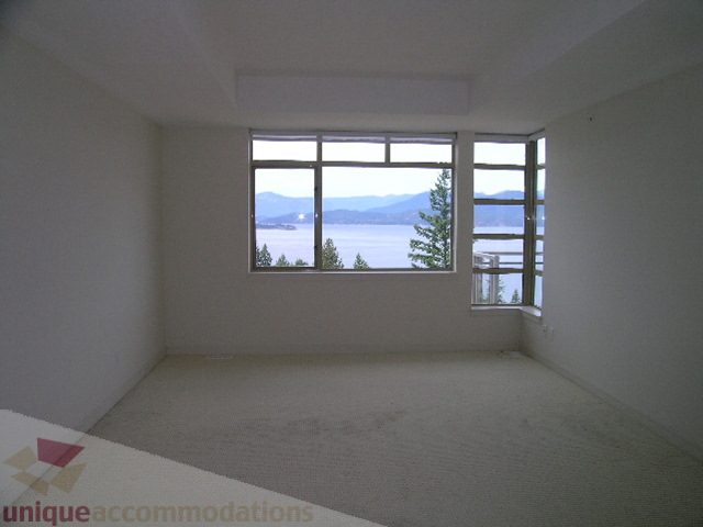 Spacious living room with large windows offering a stunning view of the mountains and water. - 8601 Seascape Place, West Vancouver