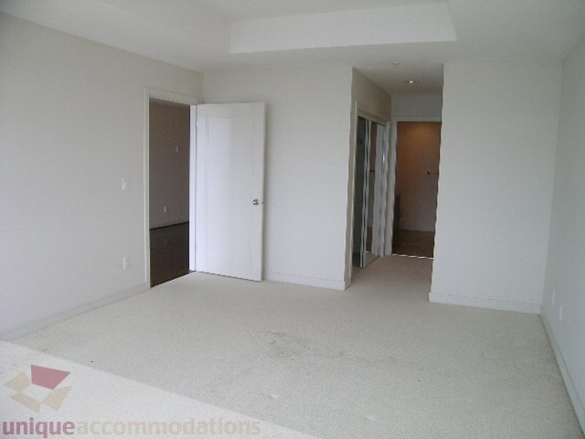 Spacious living room with white walls, carpeted floor, and access to a den. - 8601 Seascape Place, West Vancouver
