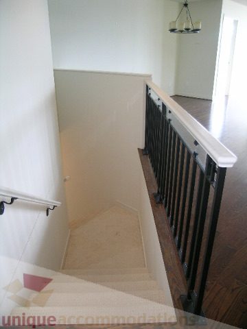 Staircase leading to upper level with wooden banister and light-colored carpet. - 8601 Seascape Place, West Vancouver