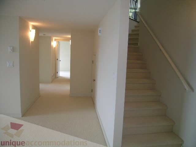 Spacious entryway leading to a bright, open floor plan with neutral carpeting and a staircase leading to upper levels.