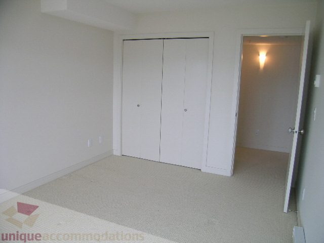 Spacious bedroom with white walls, built-in closet, and carpeted floor. - 8601 Seascape Place, West Vancouver