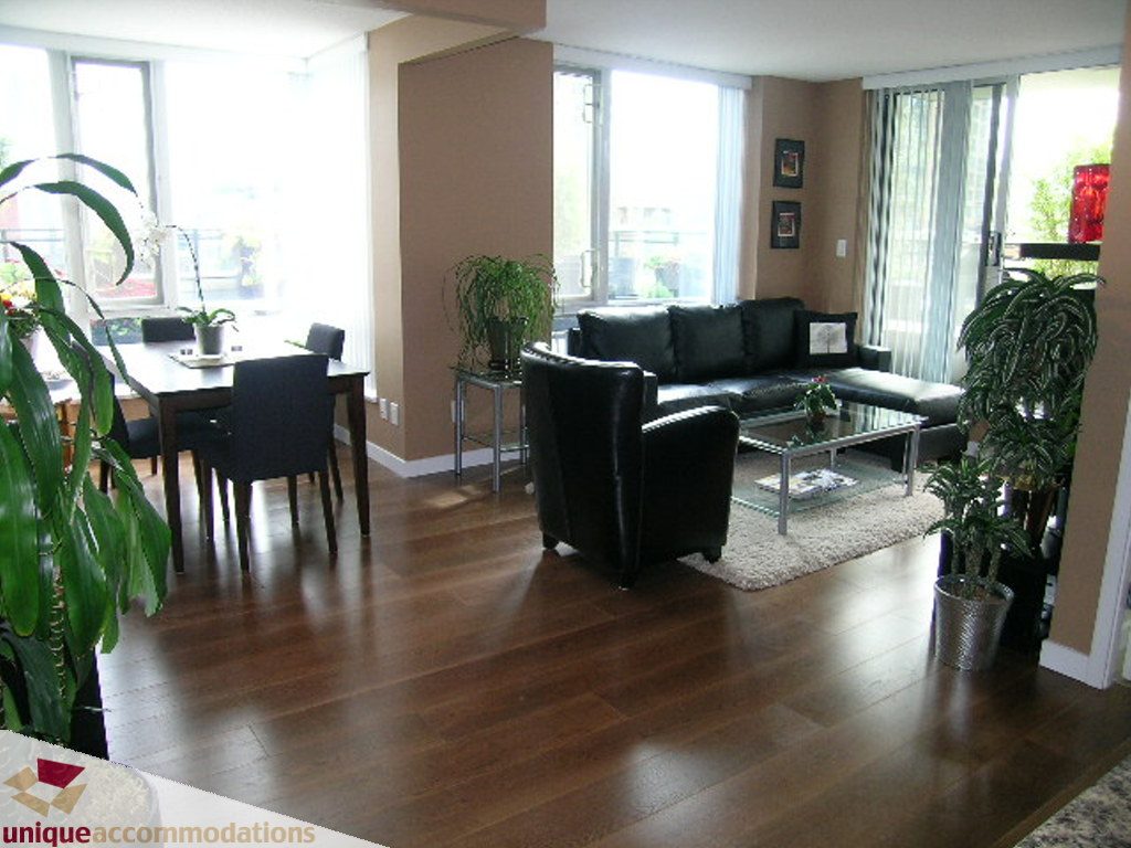 Bright living room with hardwood floors, black furniture, and large windows. - 316 - 1082 Seymour, Vancouver Downtown