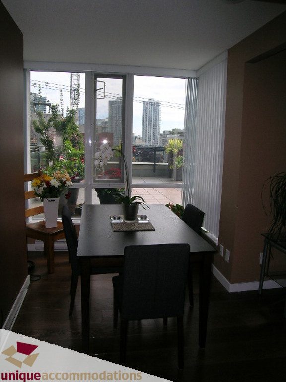 Dining area with city view, modern decor, and wooden floor. - 316 - 1082 Seymour, Vancouver Downtown