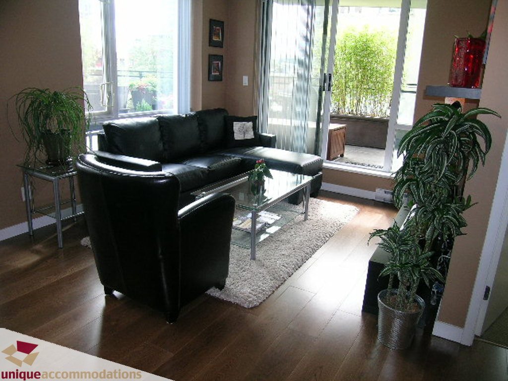 Furnished living room with hardwood floors, black leather furniture, and large windows. - 316 - 1082 Seymour, Vancouver Downtown