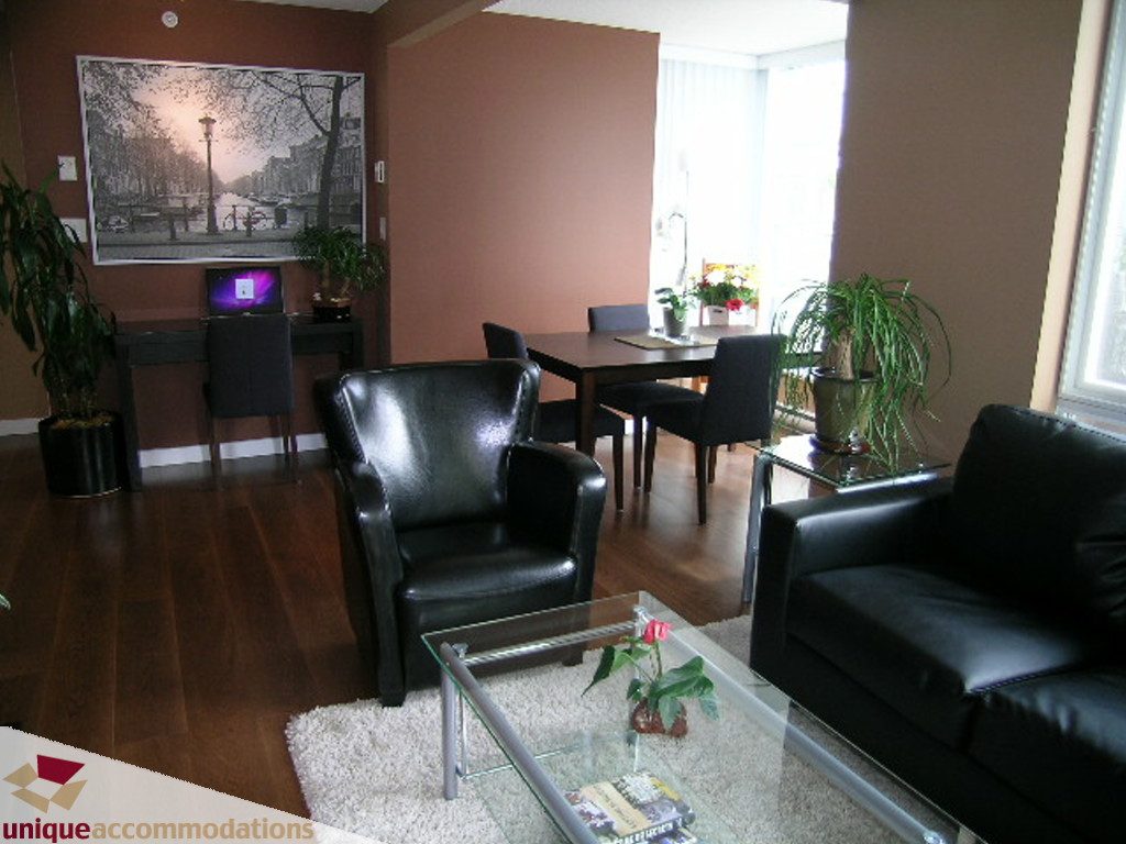 Bright living room with hardwood floors, black leather furniture, and a glass coffee table. - 316 - 1082 Seymour, Vancouver Downtown