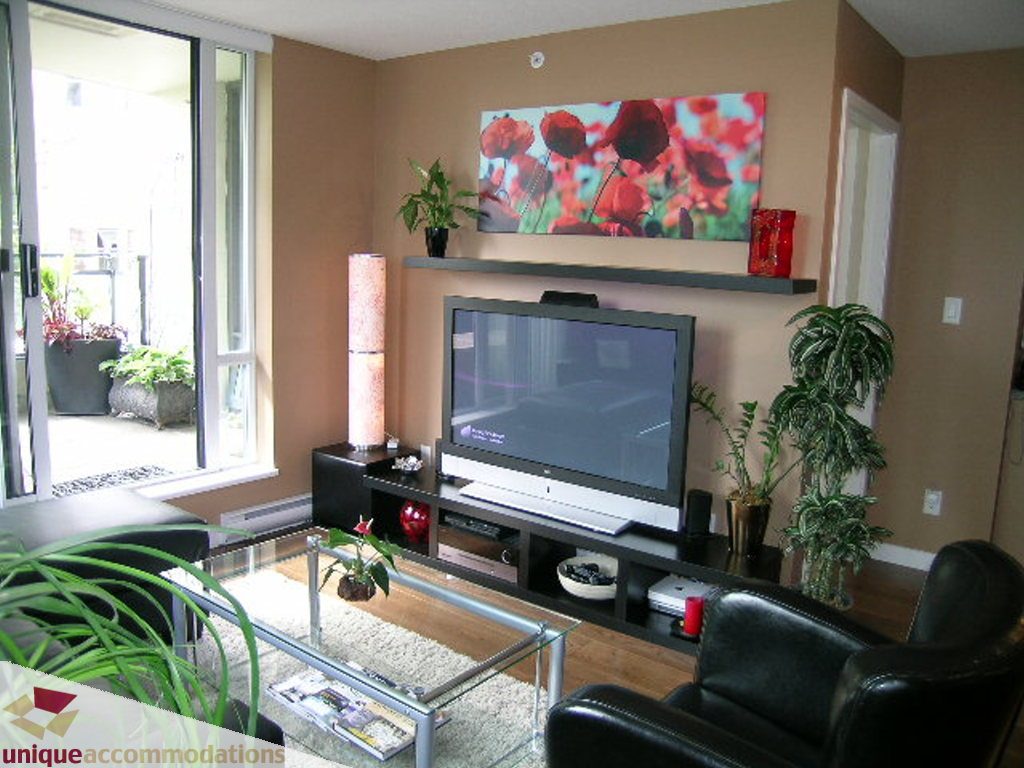 Furnished living room with hardwood floors, modern TV, and large windows. - 316 - 1082 Seymour, Vancouver Downtown
