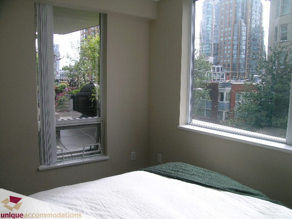Bright bedroom with city view and large windows, showcasing urban skyline. - 316 - 1082 Seymour, Vancouver Downtown
