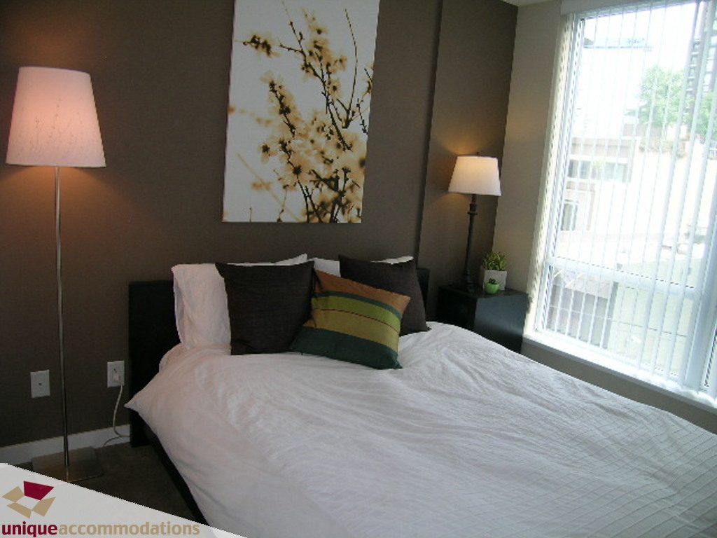 Bright bedroom with a king-sized bed, floral artwork, and a city view through the window. - 316 - 1082 Seymour, Vancouver Downtown