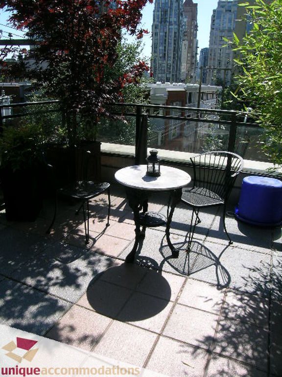 Furnished balcony with city view, patio furniture, and potted plants. - 316 - 1082 Seymour, Vancouver Downtown