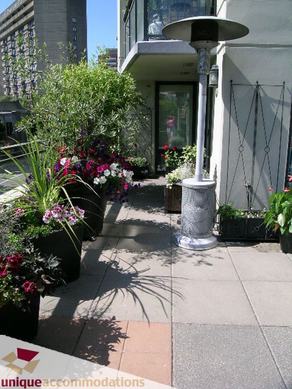 Furnished patio with potted plants and a gas heater, city view. - 316 - 1082 Seymour, Vancouver Downtown