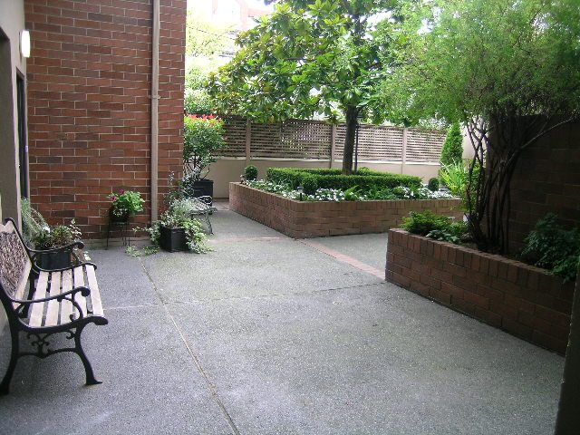 Cozy patio with brick walls, greenery, and a bench. - 108 - 1279 Nicola Street, Vancouver Downtown