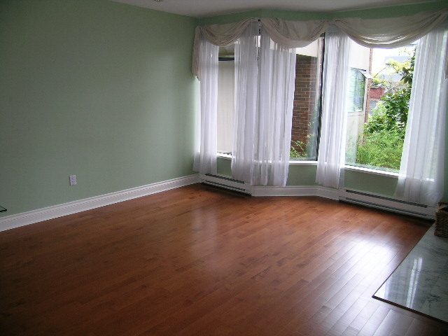 Bright living room with hardwood floors and white curtains, natural light flooding in. - 108 - 1279 Nicola Street, Vancouver Downtown