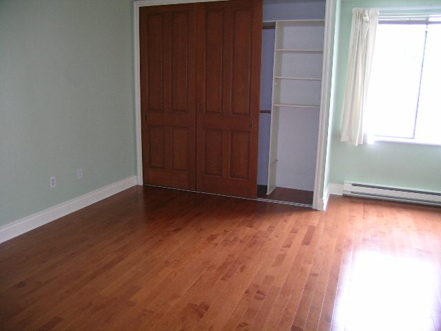 Bright living room with hardwood floors and a wooden door. - 108 - 1279 Nicola Street, Vancouver Downtown