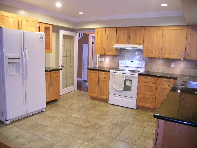 Bright kitchen with light wood cabinets, granite countertops, and a tiled floor. - 992 Canyon Blvd, North Vancouver