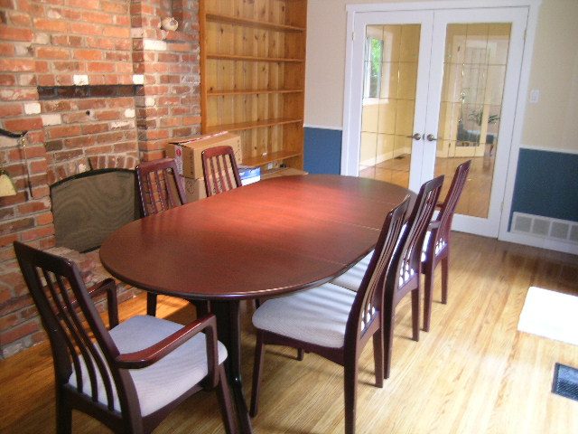 Dining room with wooden table, chairs, brick wall, and French doors leading outside. - 992 Canyon Blvd, North Vancouver