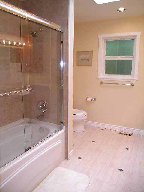 Bright bathroom with glass shower, beige walls, and a window. - 992 Canyon Blvd, North Vancouver