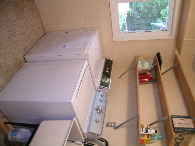 Bright laundry room with white cabinets and countertop, window view. - 992 Canyon Blvd, North Vancouver