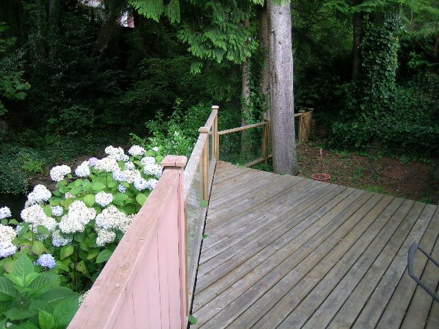 Deck with wooden railings and blooming hydrangeas, surrounded by lush greenery. - 992 Canyon Blvd, North Vancouver