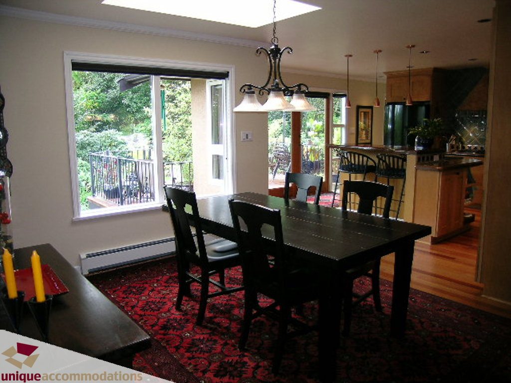 Furnished dining area with hardwood floors, red rug, and view to balcony. - 1385 East 15th Street, North Vancouver