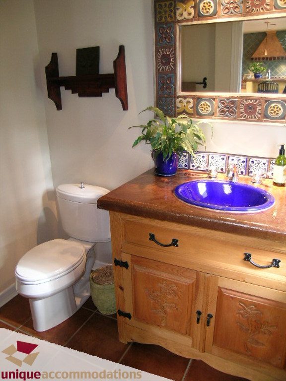 Bathroom with wooden vanity, blue sink, and decorative mirror. - 1385 East 15th Street, North Vancouver