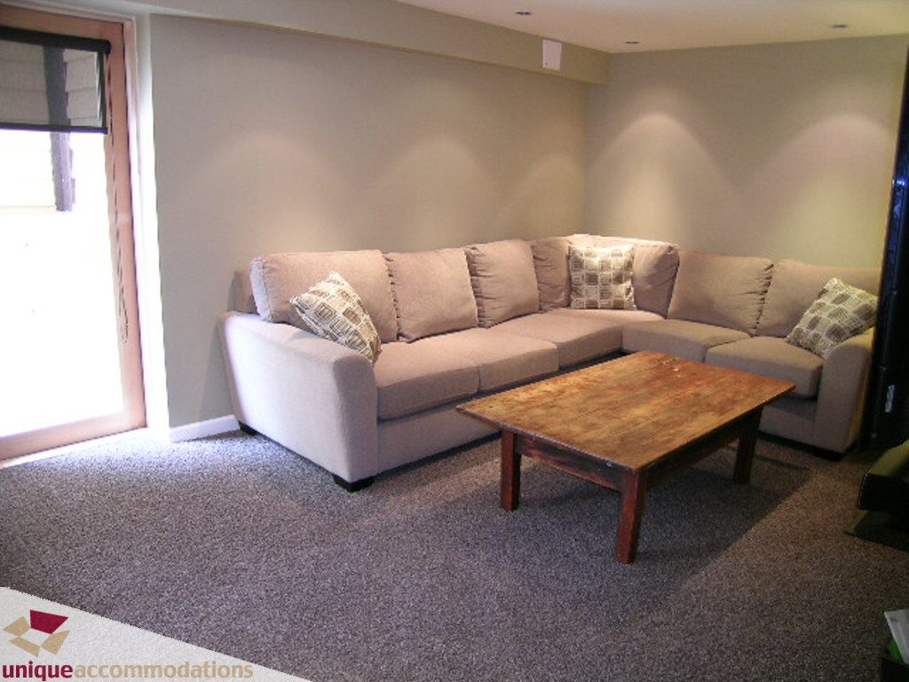 Furnished living room with a sectional sofa, wooden coffee table, and carpeted floor. - 1385 East 15th Street, North Vancouver