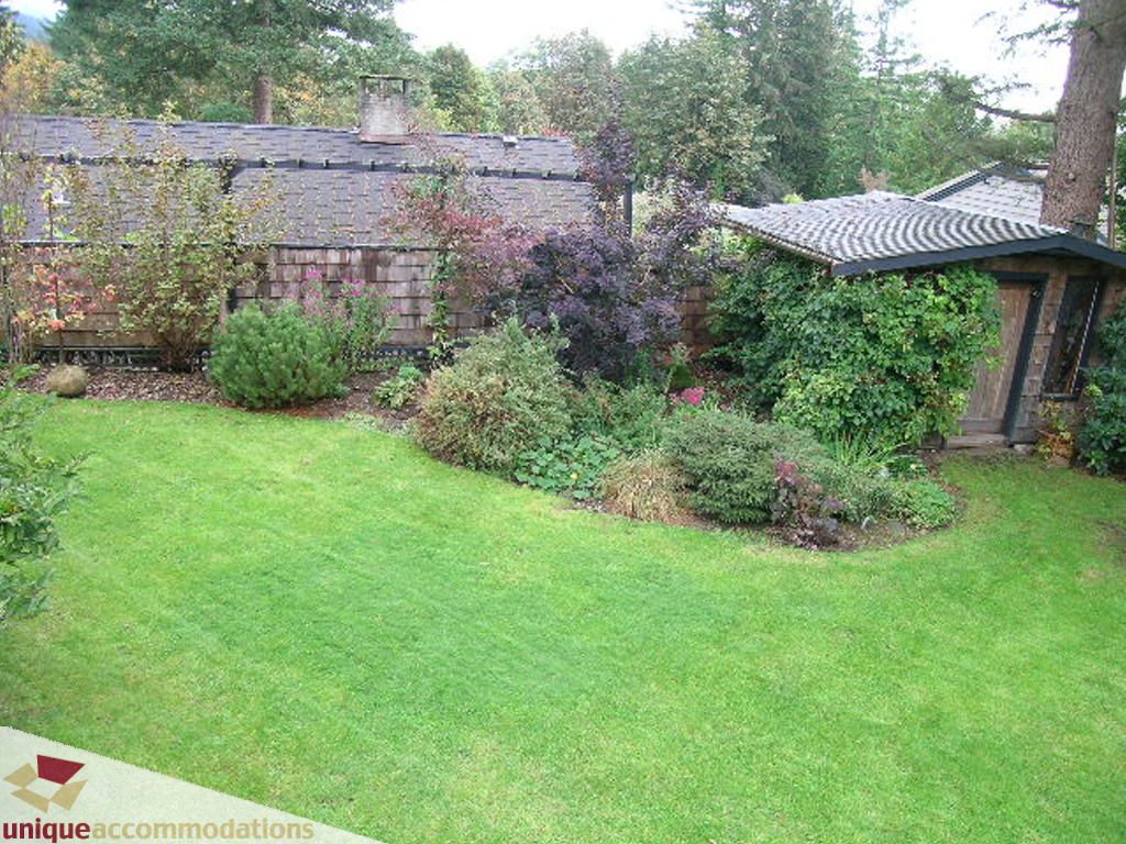 Spacious backyard with lush green lawn and garden beds. - 1385 East 15th Street, North Vancouver