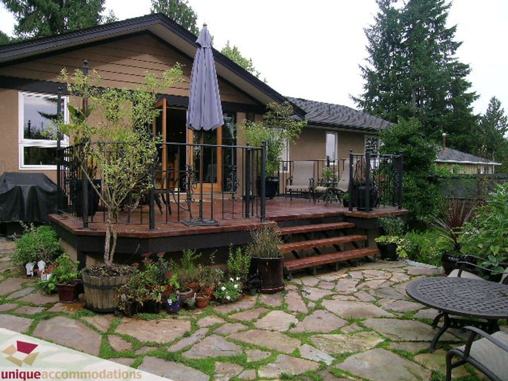 Furnished patio with stone walkway, wooden deck, and potted plants. - 1385 East 15th Street, North Vancouver