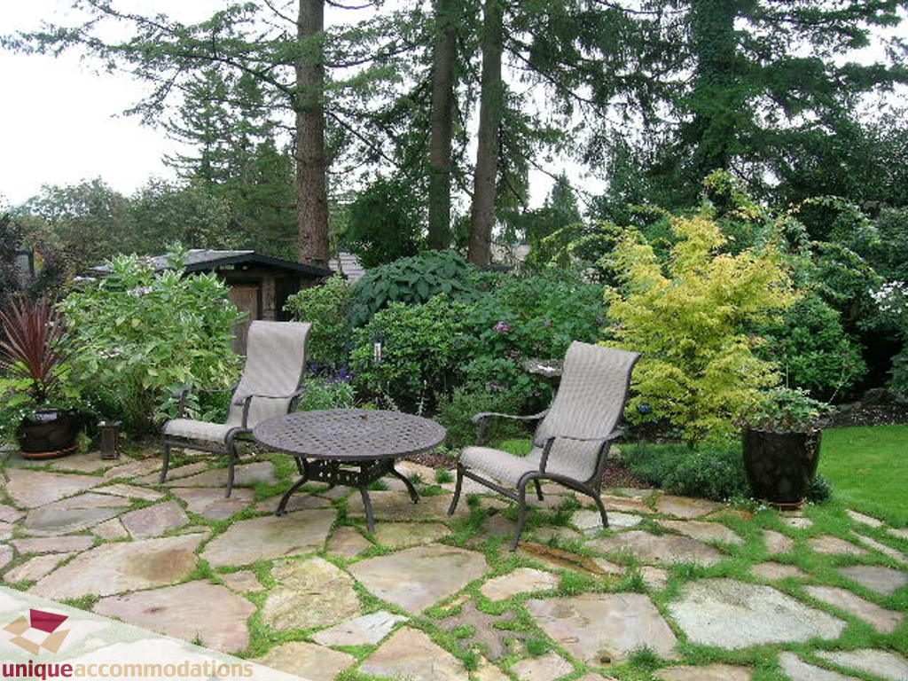 Furnished patio with stone flooring, outdoor furniture, and lush greenery. - 1385 East 15th Street, North Vancouver
