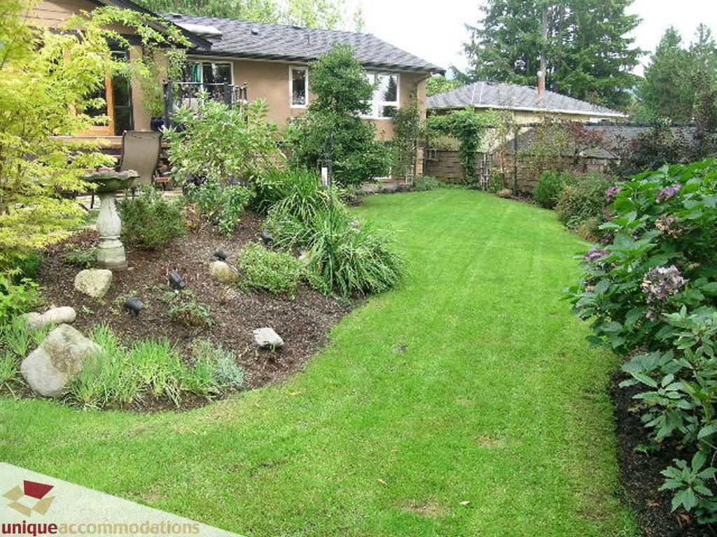 Furnished backyard with lush green lawn and garden beds. - 1385 East 15th Street, North Vancouver