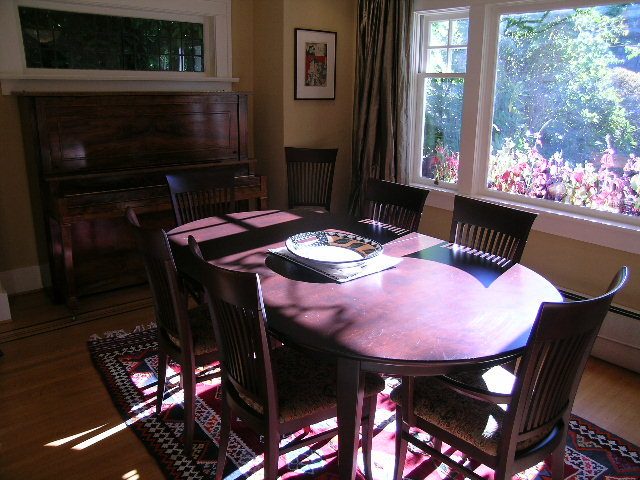 Dining room with wooden table, chairs, and large window with garden view. - 4663 Bellevue Drive, Vancouver West Side