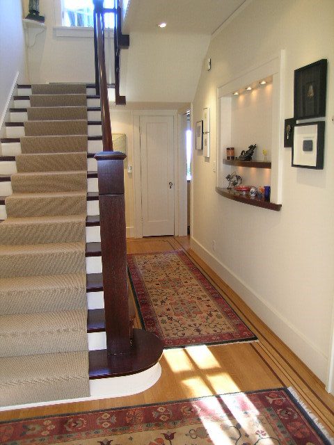 Foyer with wooden staircase, patterned rug, and wall shelf. - 4663 Bellevue Drive, Vancouver West Side