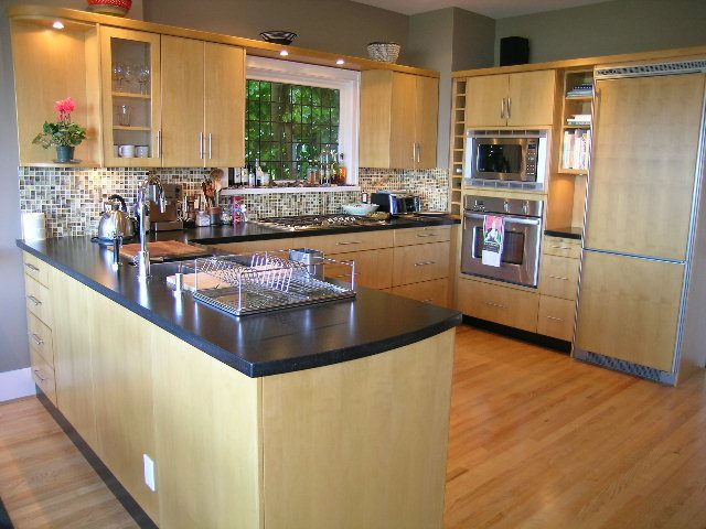 Bright kitchen with light wood cabinets, black countertops, and hardwood floors. - 4663 Bellevue Drive, Vancouver West Side