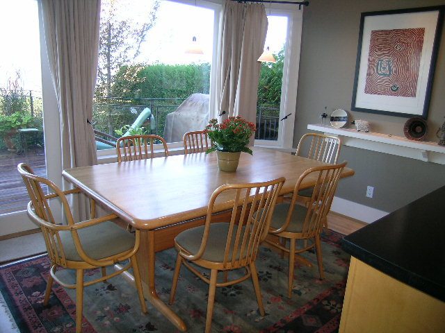 Bright dining area with wooden chairs, black countertops, and a view of greenery outside. - 4663 Bellevue Drive, Vancouver West Side