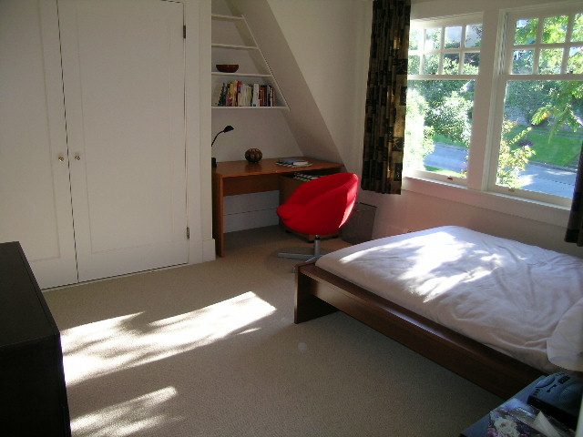 Bright bedroom with a large window, red chair, and wooden desk. - 4663 Bellevue Drive, Vancouver West Side
