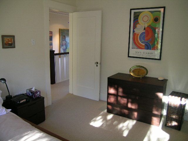 Bright bedroom with wooden furniture and a colorful abstract painting on the wall. - 4663 Bellevue Drive, Vancouver West Side