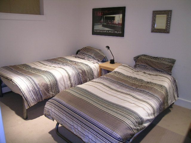 Furnished bedroom with two single beds, striped bedding, and a bedside lamp. - 4663 Bellevue Drive, Vancouver West Side