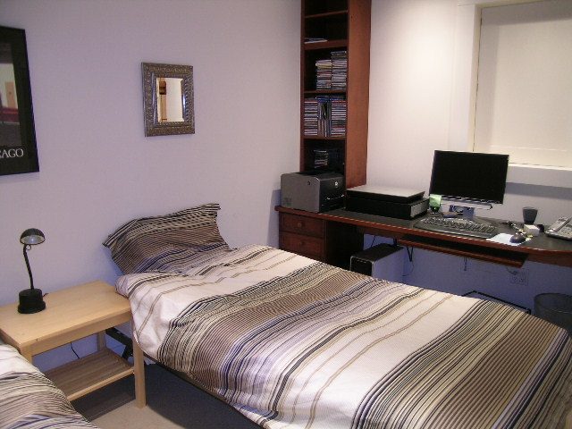 Bright bedroom with striped bedding and desk setup, perfect for a cozy stay. - 4663 Bellevue Drive, Vancouver West Side
