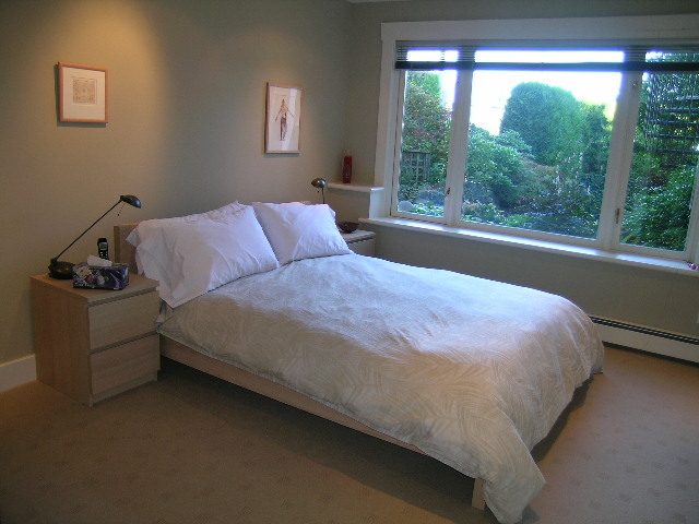Bright bedroom with large windows, white bedding, and a cozy reading nook. - 4663 Bellevue Drive, Vancouver West Side