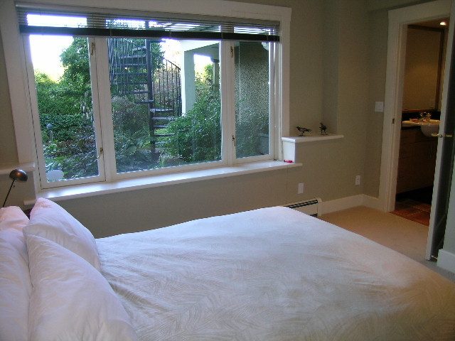 Bright bedroom with large windows, hardwood floors, and a cozy bed setup. - 4663 Bellevue Drive, Vancouver West Side