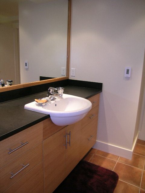 Modern bathroom with dark countertops and wooden cabinets. - 4663 Bellevue Drive, Vancouver West Side