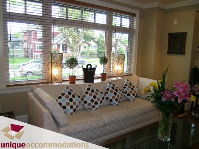 Furnished living room with large windows, checkered sofa, and vibrant floral arrangements. - 3030 West 15th Avenue, Vancouver West Side