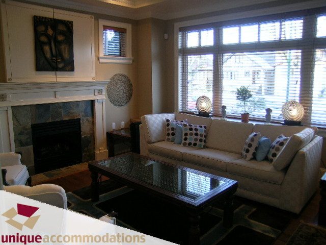 Furnished living room with large windows, modern decor, and a cozy fireplace. - 3030 West 15th Avenue, Vancouver West Side