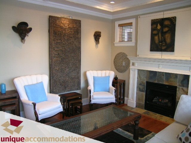 Furnished living room with a fireplace, blue armchairs, and decorative wall art. - 3030 West 15th Avenue, Vancouver West Side