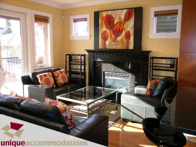Furnished living room with hardwood floors, large windows, and a vibrant floral painting above the fireplace.