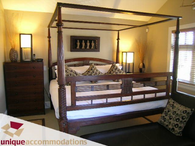 Furnished 3-bedroom + den bedroom with a four-poster bed, patterned pillows, and a dark wood dresser. - 3030 West 15th Avenue, Vancouver West Side
